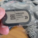 Dog tag Color com nome "Conceição Adriana", data "12/03/1991" e tipo sanguíneo "A+".