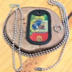 Dog tag Color com a frase "O que fazemos em vida ecoa pela eternidade" sobre madeira rústica.