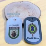 Dog tags coloridas: uma com o brasão do exército e outra com o desenho de um chacal.