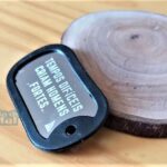 Dog Tag Fina preta com frase "Tempos difíceis criam homens fortes".