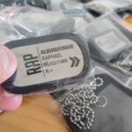 Dog tag colorida com nome "Albuquerque Raphael", data "06/03/1986" e tipo sanguíneo "A+".