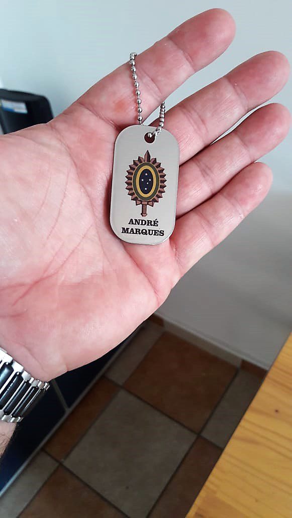 Dog tag colorida com brasão e nome "André Marques".