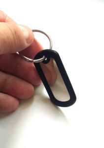 Chaveiro Dog Tag Fina mono preto em mão sobre fundo branco.