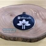 Placa Pingente Redondo em Aço Inox 316L com gravação "Madeirado" e flor estilizada. Pingente redondo em aço inox.