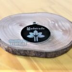 Placa Pingente Redondo em Aço Inox com gravação "Madeirado" e flor estilizada.