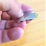 Image of a hand holding a shiny metal disc Placa Pingente Identificação Pet Cães Gatos em Aço Inox Chaveiro Dog Tag Portuguese (Brazil) Pingente aço inox para pet Mania de Metal